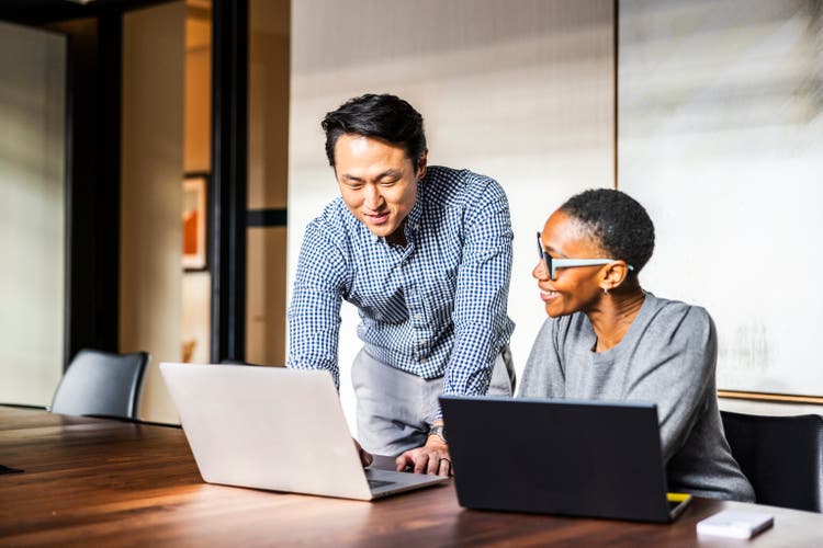 Business colleagues working on laptops in modern conference room