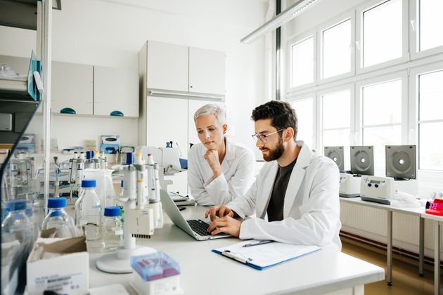 Female Scientist Assisting Male Scientist with Data Analysis in a High-Tech Laboratory