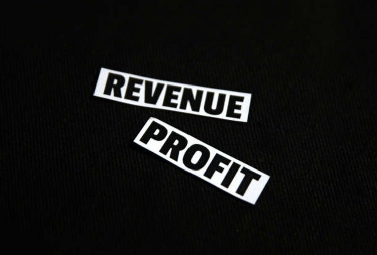 Revenue and Profit typography pieces on the black surface backdrop close up, business and finance concept background