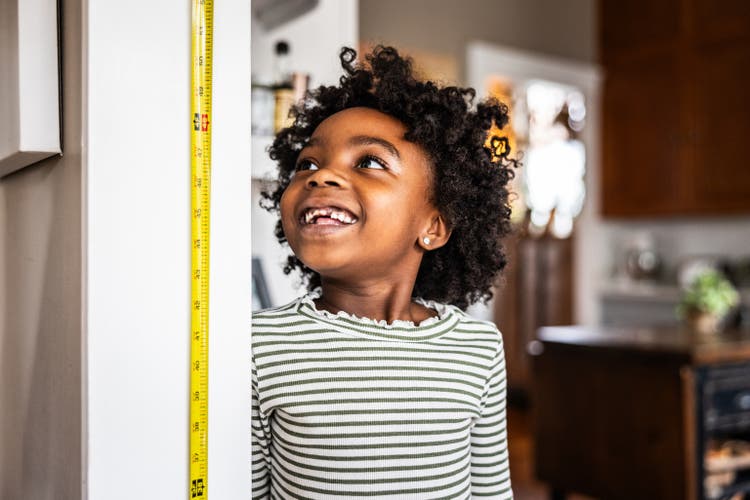 Young girl checking her height on the wall