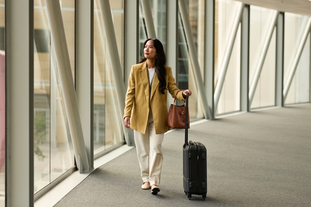 Businesswoman wheeling with luggage on elevated walkway