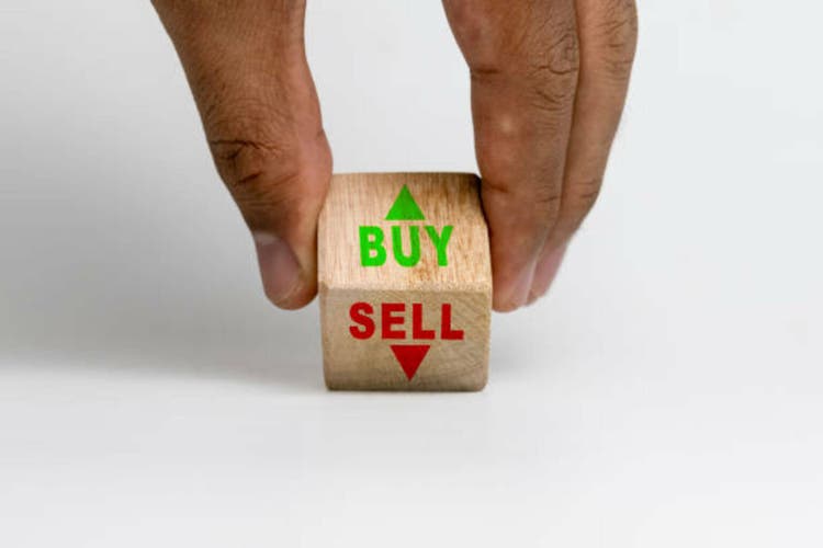male hand turning buy and sell words with up and down arrow on wooden block isolated on white background