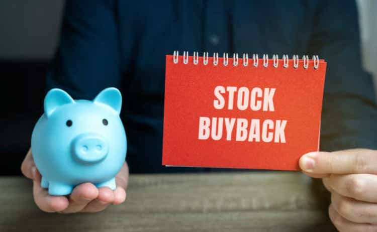 Stock buyback concept. Corporate action in which a company buys back its own shares from the open market or from its shareholders. Notes in the hands of a businessman and a piggy bank