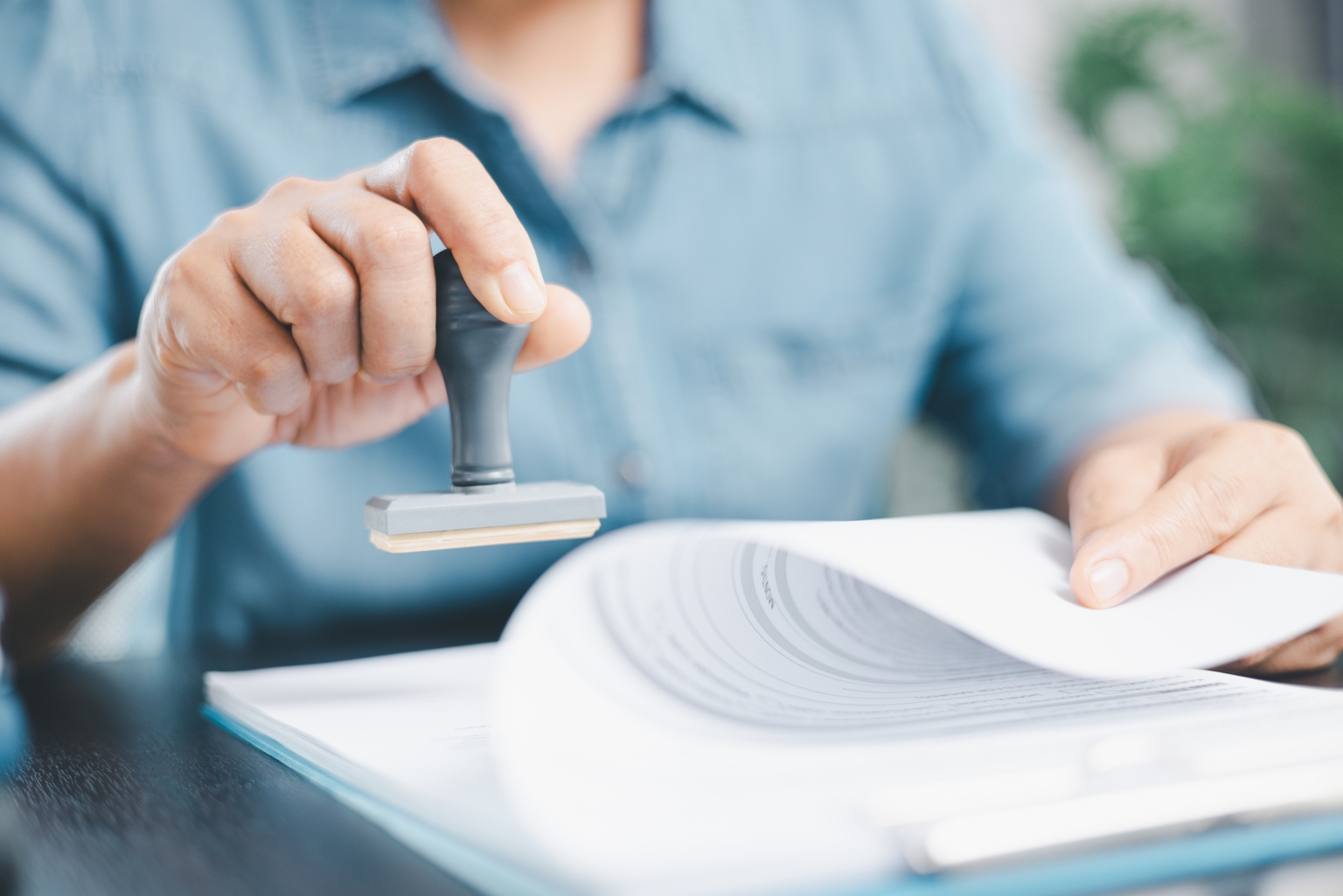 Businessman hands stamp approve on financial business approval document paper. Man hand accepted permit contract agreement. Broker manager sign contract bank guarantee approved stamp application form