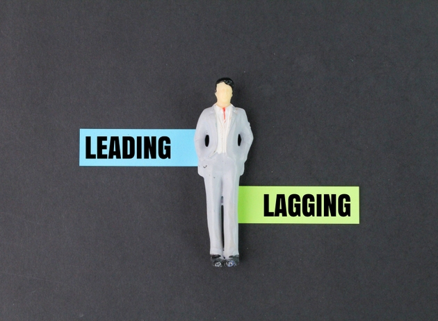miniature people and colored paper with the words leading and lagging. two types of performance indicators.