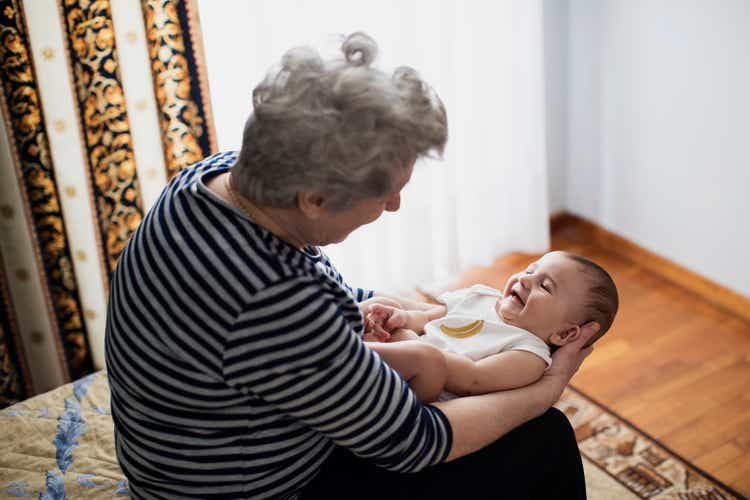 Smiling baby being held by grandmother in cozy indoor setting