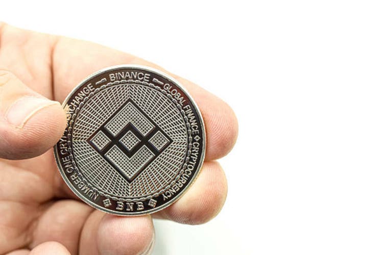 Hand showing a cryptocurrency Binance coin on white background. Space for text.