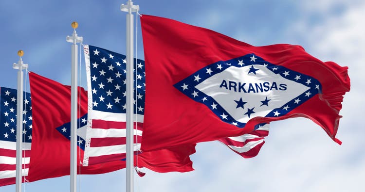 Arkansas state flags waving with the American flags on a clear day