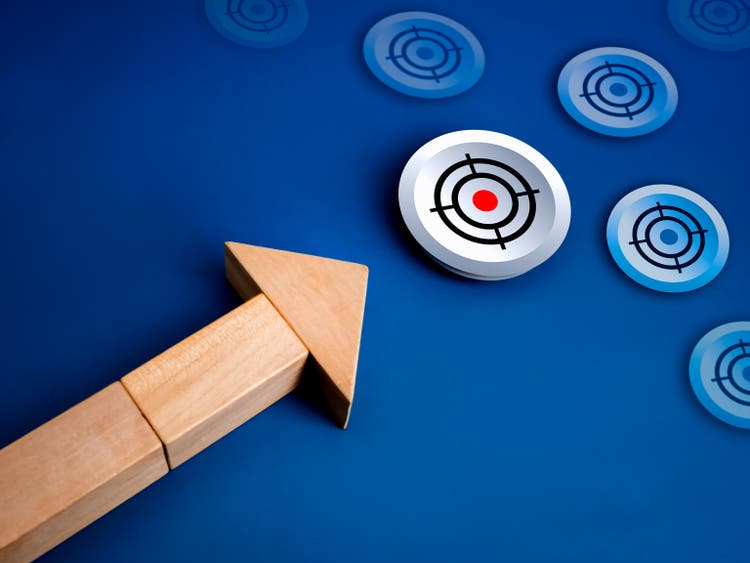 Hit the goal, the first target, leadership, business growth plan, technology trends, success aiming concept. Shooting target icon as a goals of wooden arrow blocks on blue background.