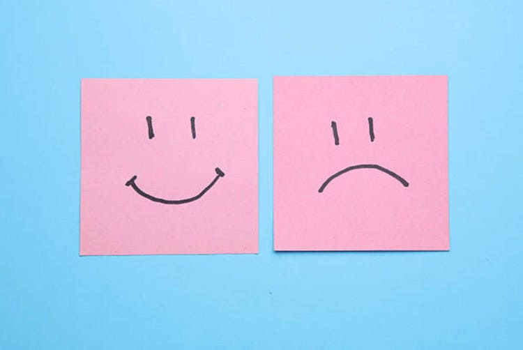 Happy and unhappy face drawn on square memo paper, blue background. Business concept