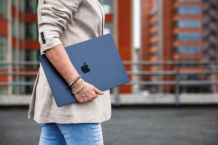Woman with Apple laptop MacBook Air with M4 chip is walking outside of office building