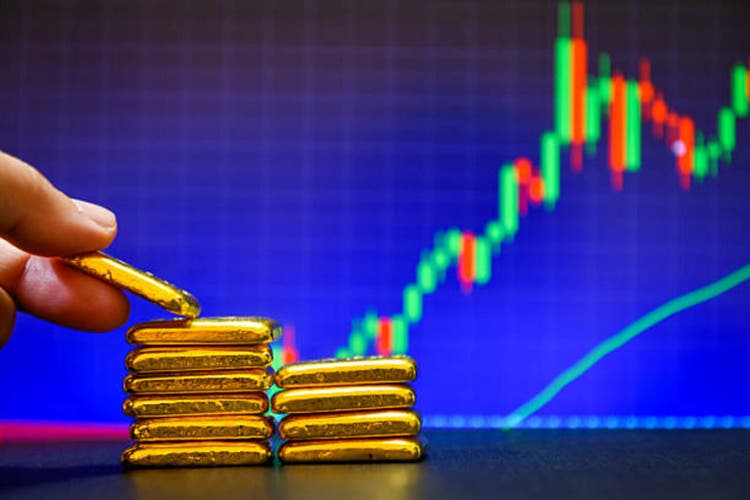 Hand holding a gold bars the candlestick chart. background