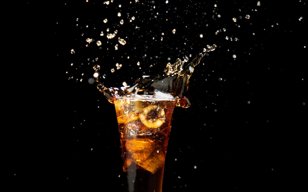 Cola drink, soda in glass with ice, refreshing splash water, isolated on black background.