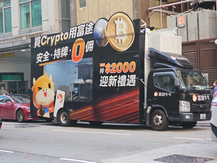 Hong Kong, China: A Futu branded promotional truck advertising cryptocurrency services, featuring Bitcoin imagery and Chinese text, parked on an urban street.
