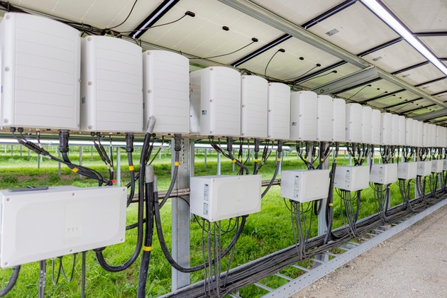 Row of multiple DC/AC current power inverter devices in photo-voltaic solar park power station.