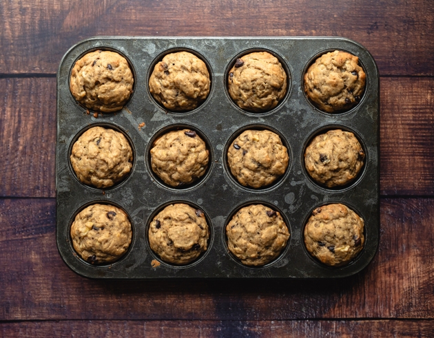 Top view of banana chocolate chip muffins in tin on wood table.