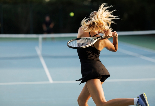 Young female tennis player hitting the ball
