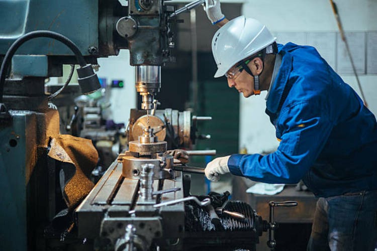 Asian male engineer working on lathe
