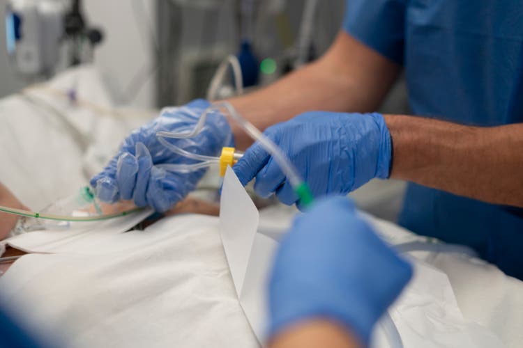 Medical team placing iv catheter into patient"s arm in hospital operating room