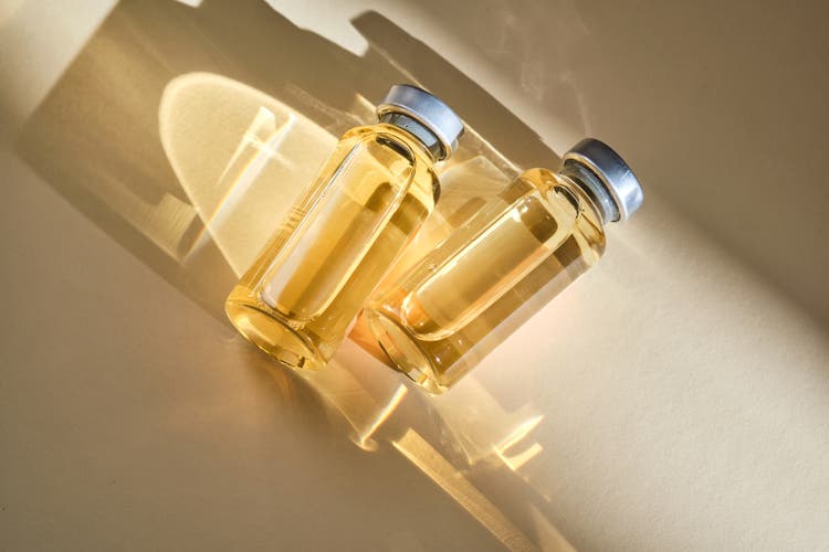 Injection vials with medicinal product in sunlight on beige background.