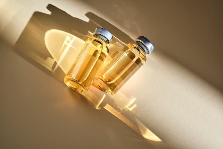 Injection vials with medicinal product in sunlight on beige background.
