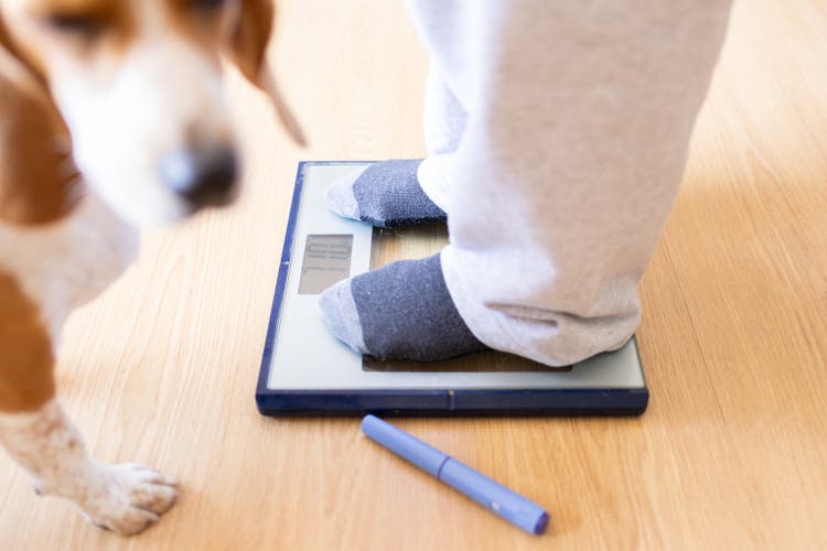 Woman weighing herself on a scale with semaglutide injection for weight loss