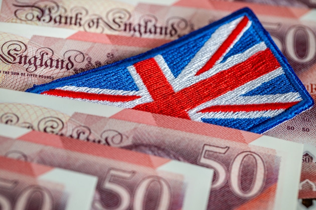 The flag of Great Britain sticking out from between money. Business concept. Financial center. Market analysis, British pound exchange rate, United Kingdom economy