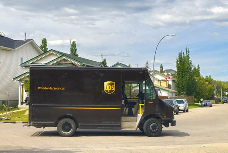 A familiar UPS truck navigates a tree-lined residential street, symbolizing essential delivery services connecting communities in a digital age.