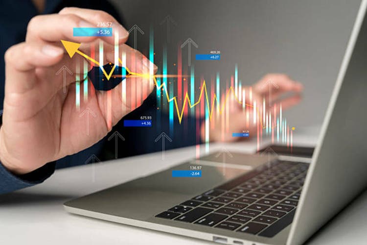 Hand analyzing stock market graph and financial candlestick chart with futuristic data on laptop screen