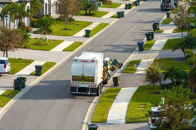 Garbage truck picking up trash bins on suburban street side