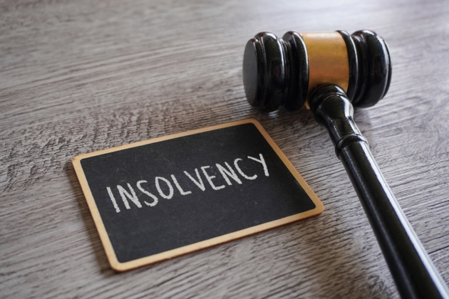 A judge"s gavel and a chalkboard with text INSOLVENCY.