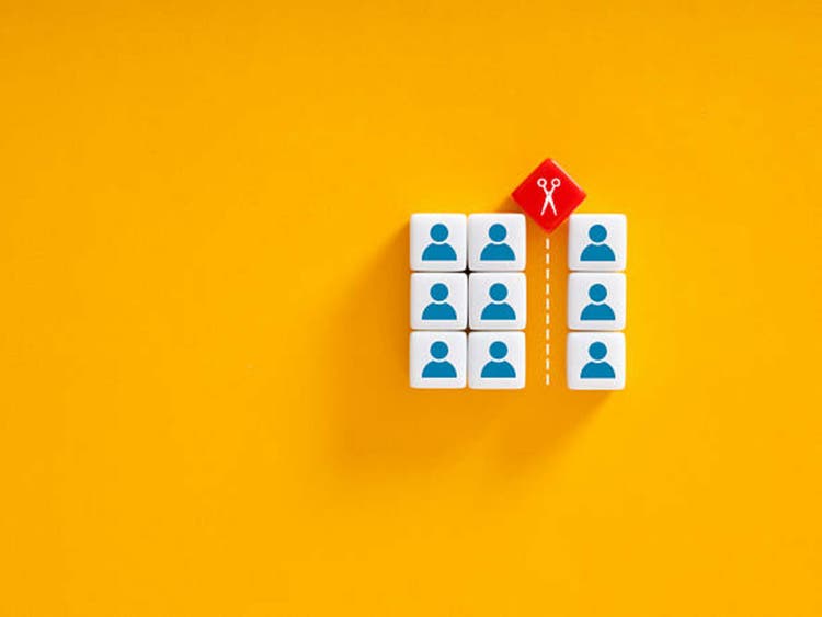 Scissors separating employees on colorful blocks representing staff reduction