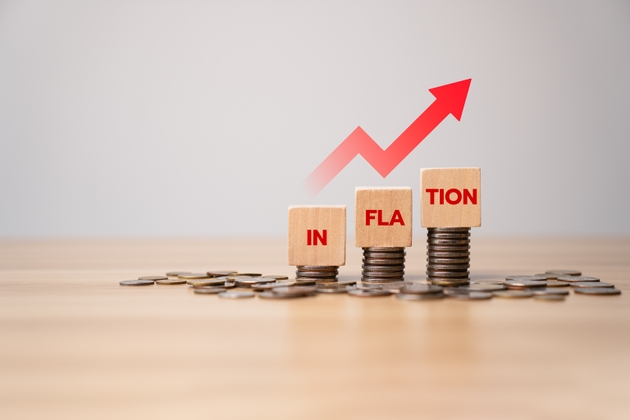 Inflation concept with rising red arrow and stacked coins under wooden blocks spelling INFLATION, symbolizing economic pressure, financial impact, cost increase, and monetary devaluation
