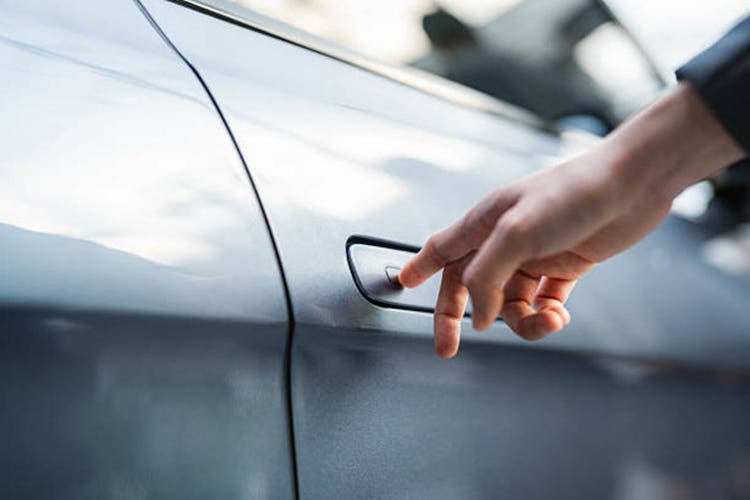 A woman pressing the button on the door handle to unlock the door of her EV car