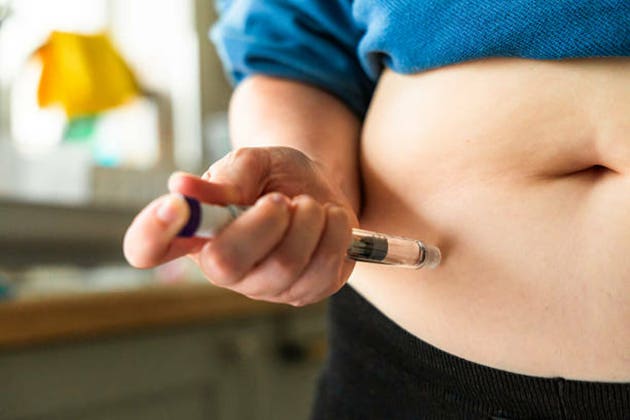 Woman using injection pen to administer weight loss drug