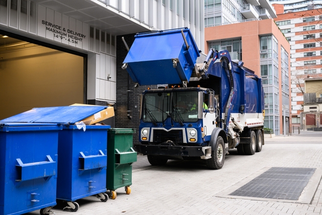 Garbage Truck Lifting Recycling Bin in Urban Alley