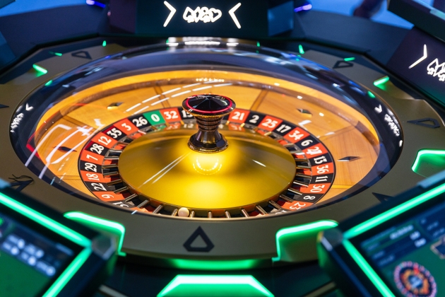 Casino electronic roulette wheel with glowing neon lights and spinning ball, showcasing gambling, betting and entertainment atmosphere in a luxury gaming environment