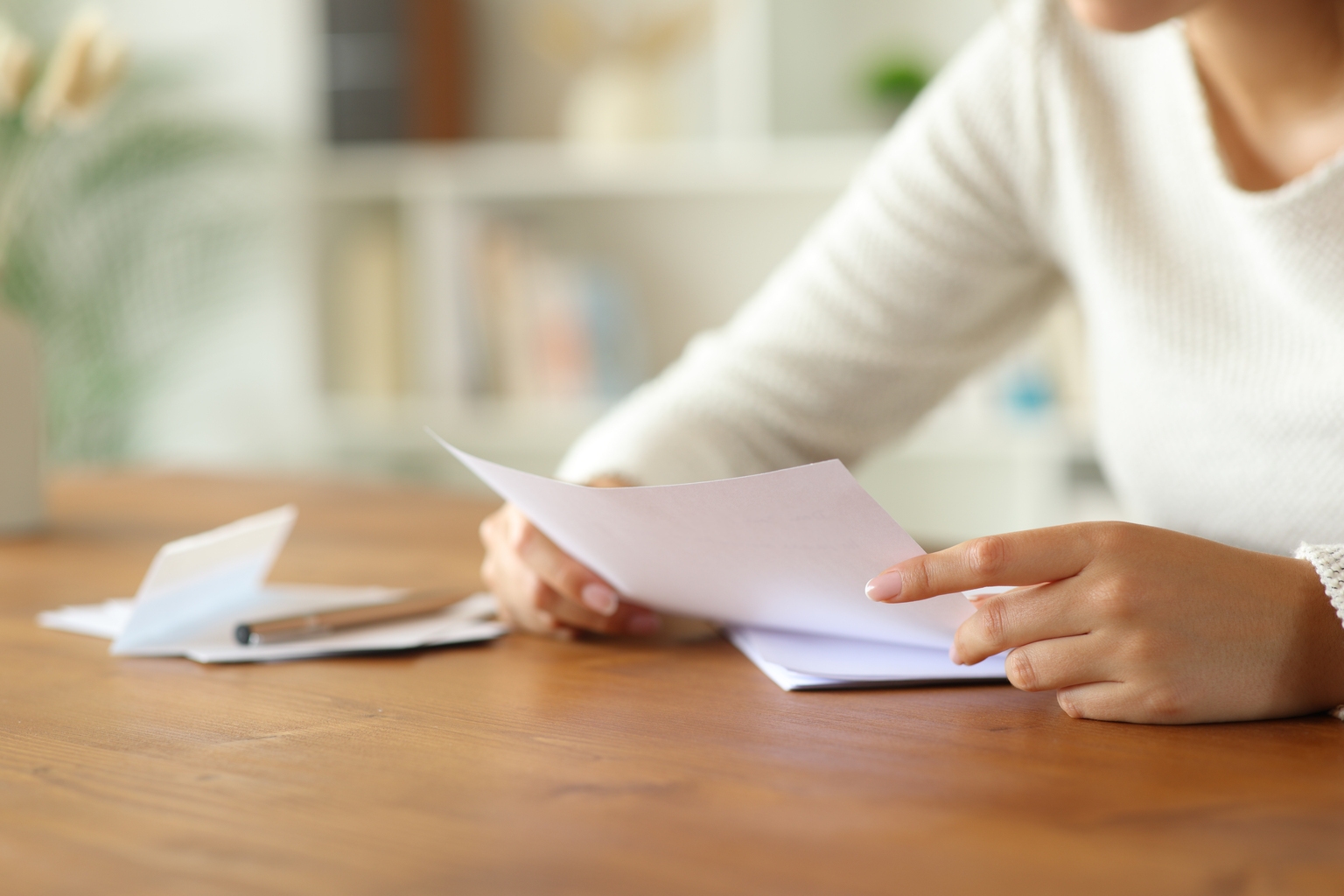 Woman hands holding and reading letter at home