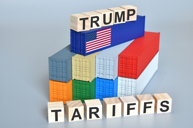 Wood cubes with Trump Tariffs words over containers with flag of US. Concept for the new tariffs imposed by US President Donald Trump.