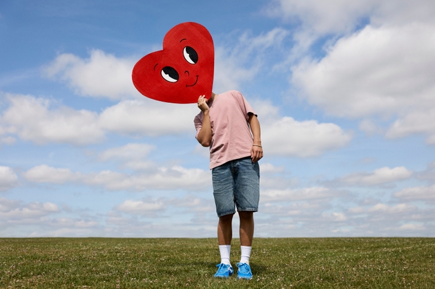 Man covering face with heart shaped cut out