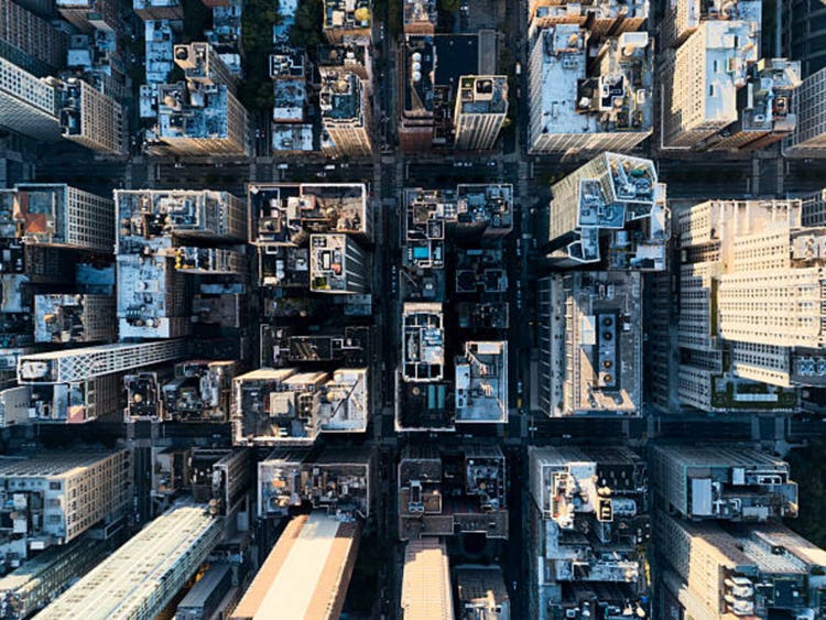 Aerial view of Midtown Manhattan skyline at sunset with iconic buildings and Hudson River in background. g