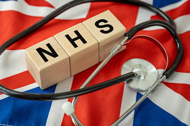 NHS written on wooden cubes. Symbol of healthcare in the UK. National Health Service. Medical concept. British health. British flag and a doctor stethoscope.
