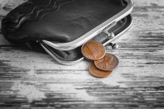One cent coins falling out of old wallet on worn wooden table, pension support, small cash money, poverty and low social benefits.