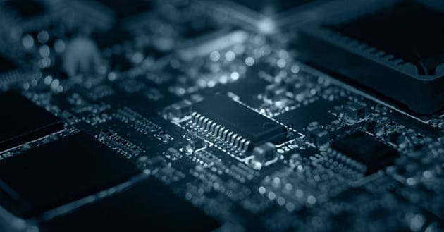 Close-up view of a detailed electronic circuit board with components illuminated in a dark environment