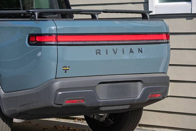 Rear view of a Rivian R1T electric pickup truck parked in a residential driveway