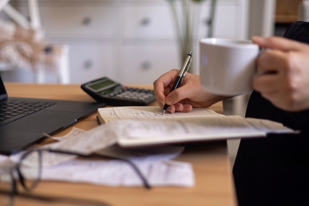 Close up of a mid adult woman checking her energy bills at home, sitting in her living room. She has a worried expression