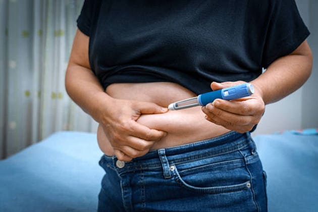 Person injecting insulin pen into abdomen for diabetes treatment
