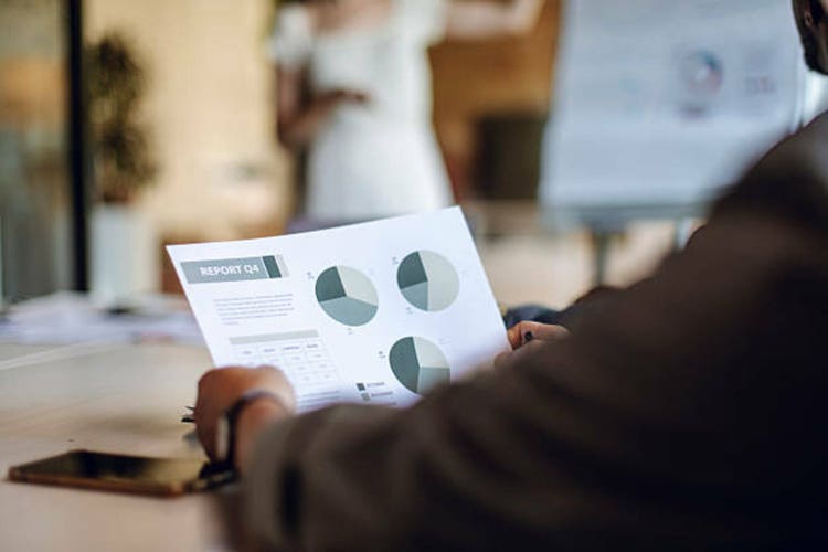 Business Person Reviewing Quarterly Report During Meeting in Office Setting