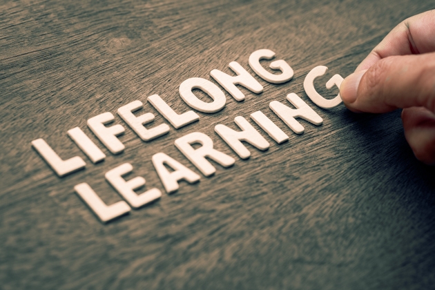 Hand arranging wooden letters to form the phrase Lifelong Learning