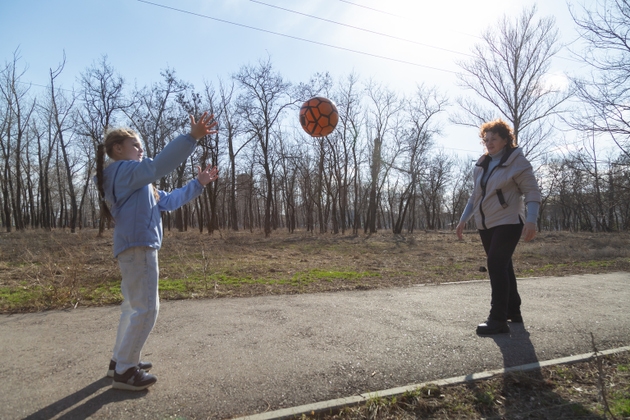 Grandmother and granddaughter having fun playing with a ball in the forest.